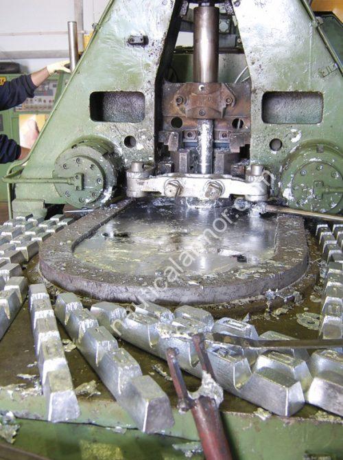 Nautical Armor zinc anode production machine with cast anodes on the table in a foundry setting. Zinc high-pressure injection machine (worker face blurred)