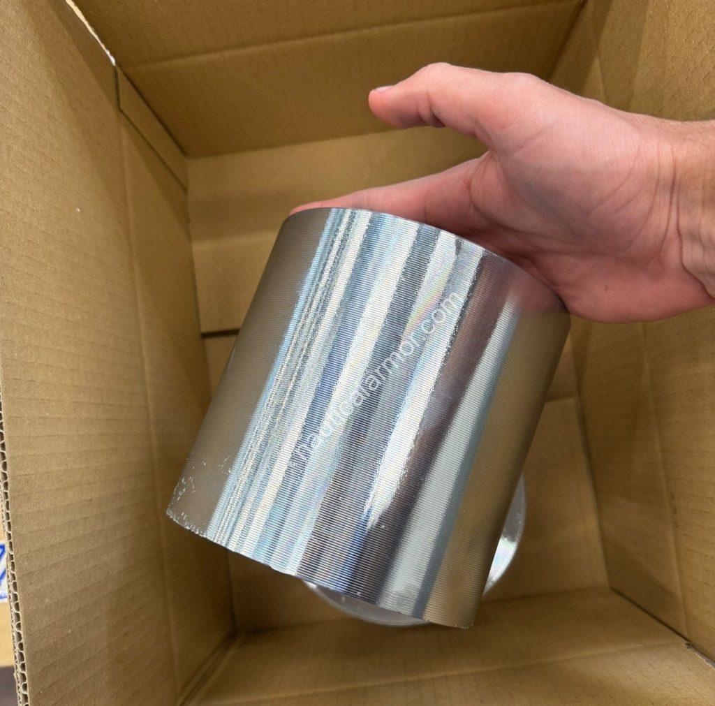 Hand holding a large Nautical Armor propeller anode above a cardboard box.
