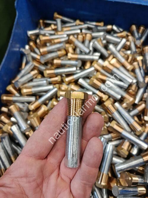 Hand holding a Nautical Armor pencil engine anode with brass thread in front of a bin filled with matching parts.