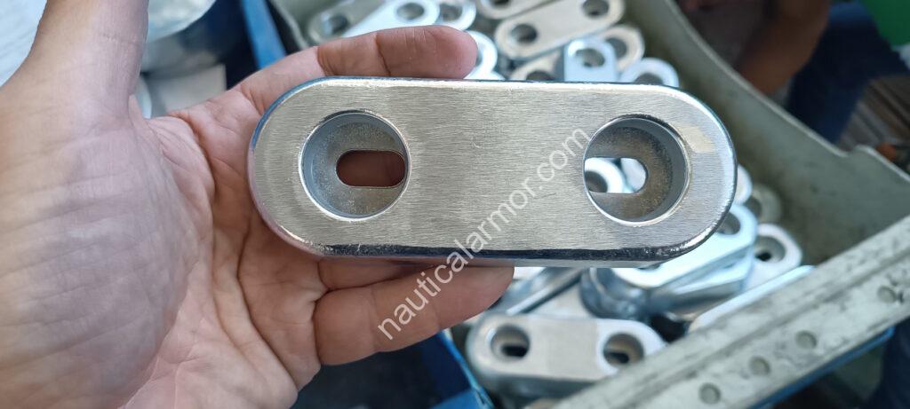 Hand holding a Nautical Armor bolt-on sacrificial anode BLT 800220 in front of anode bins.