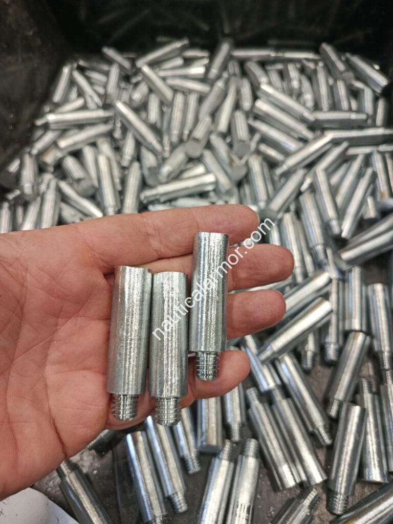Close-up of pencil sacrificial anodes held in hand above a bin filled with similar Nautical Armor anodes.