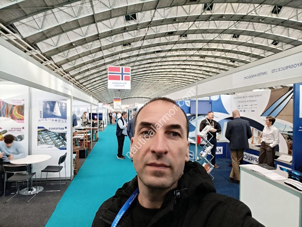 Gvapo Tripinović, founder of Nautical Armor, standing inside a marine trade fair hall at METS 2025, with exhibition booths, marine equipment displays, and visitors in the background
